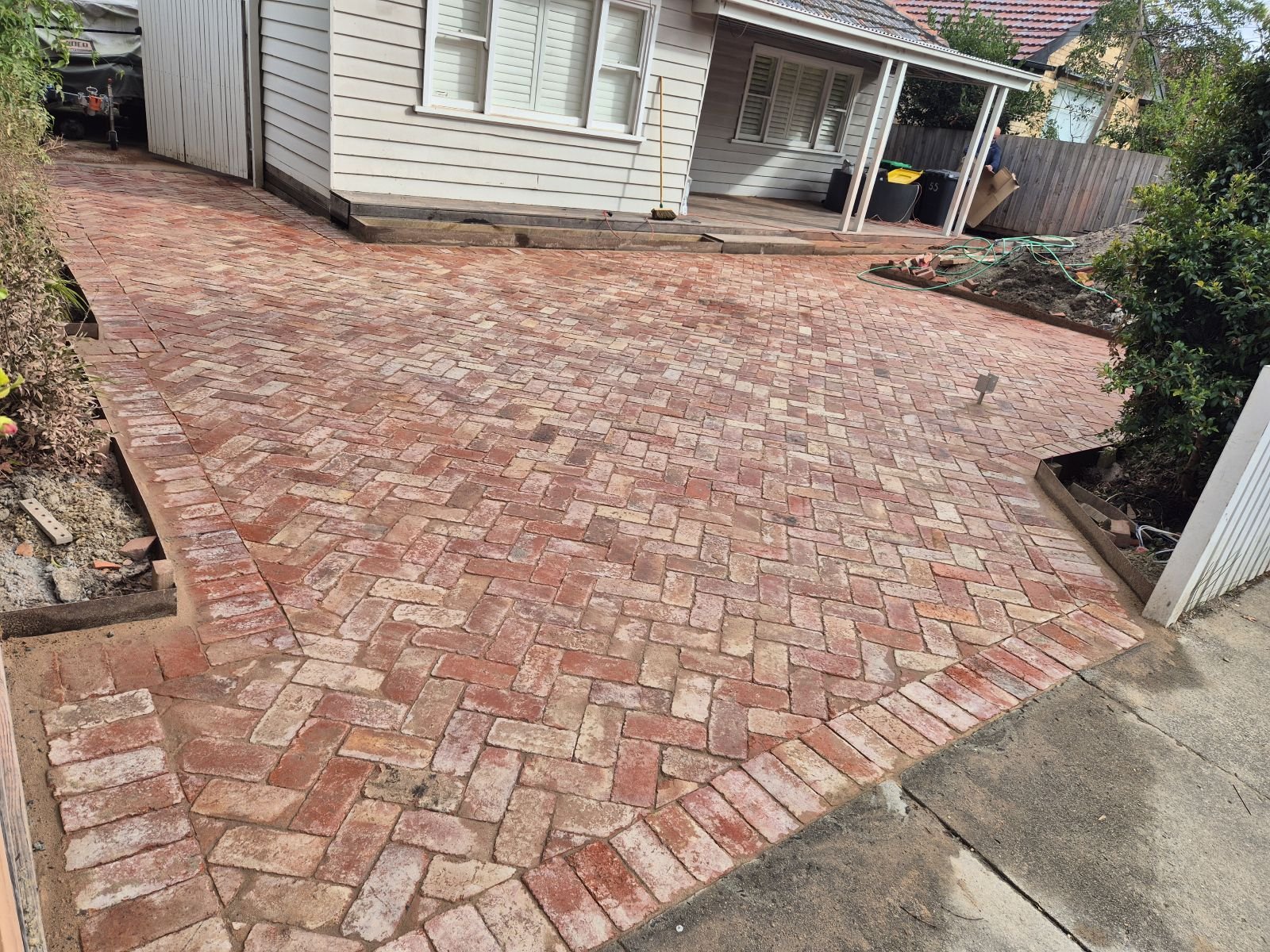 Recycled brick herringbone courtyard and driveway in front of a weatherboard home